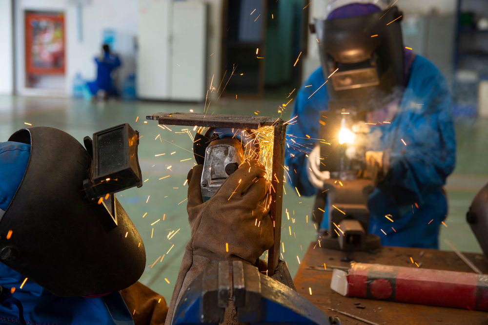 workers,cutting,metal,sheets,with,electric,grinder,in,the,workshop.